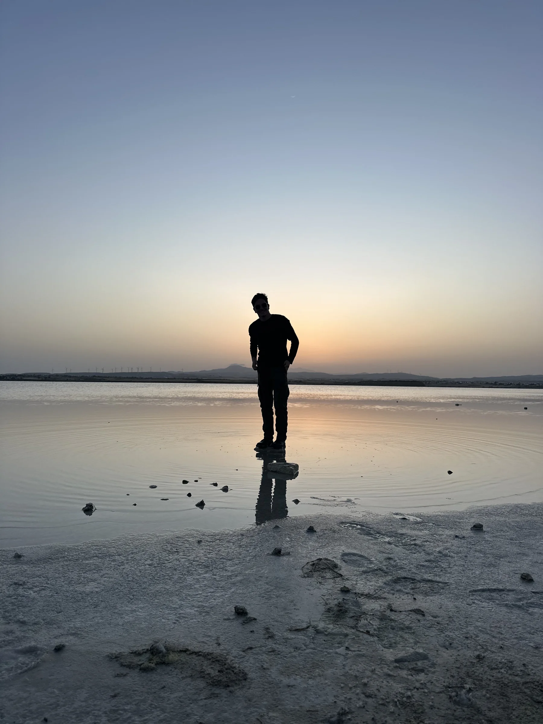 Will DeVito standing on a shallow salt flat at dusk, mountains on the horizon